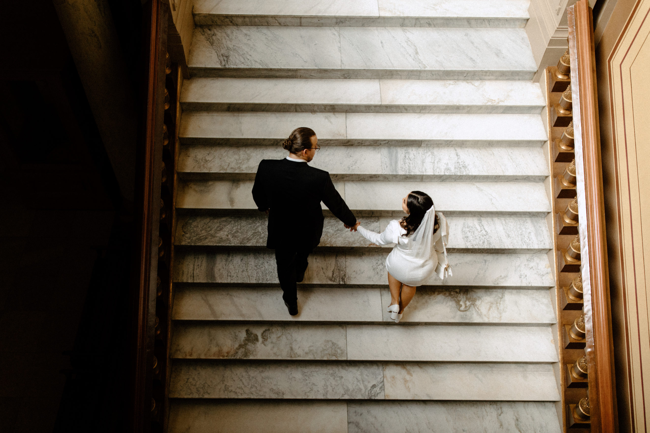 Couple walking up stairs of courthouse in Indianapolis holding hands