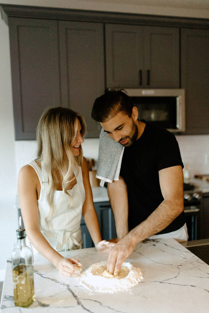 Couple making homemade pasta during in-home Indiana engagement session