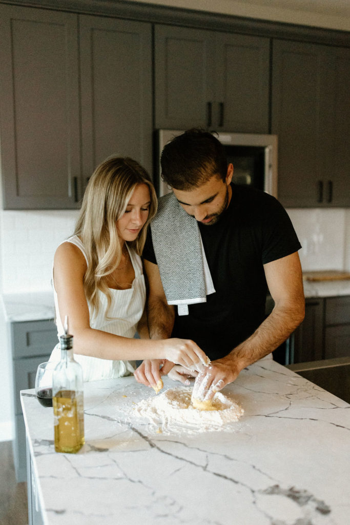 Couple making homemade pasta during in-home Indiana engagement session