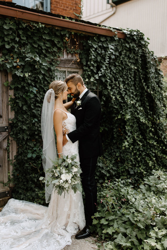 Bride and broom posing for wedding portraits before sage green and white color schemes wedding