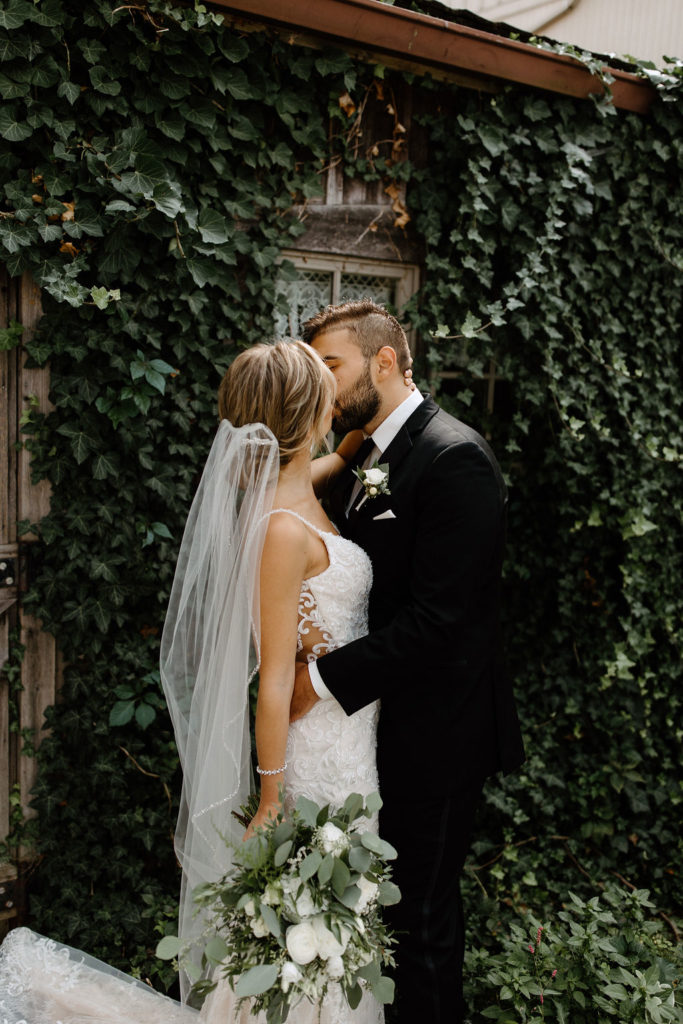 Bride and broom posing for wedding portraits before sage green and white color schemes wedding