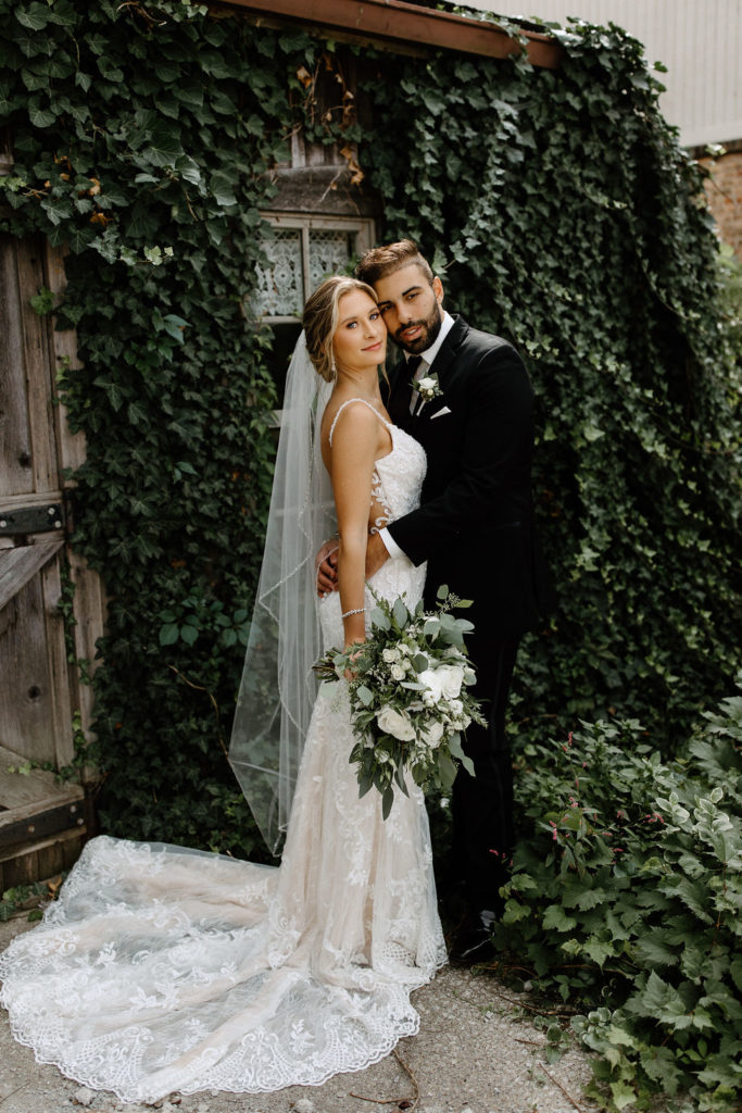 Bride and broom posing for wedding portraits before sage green and white color schemes wedding