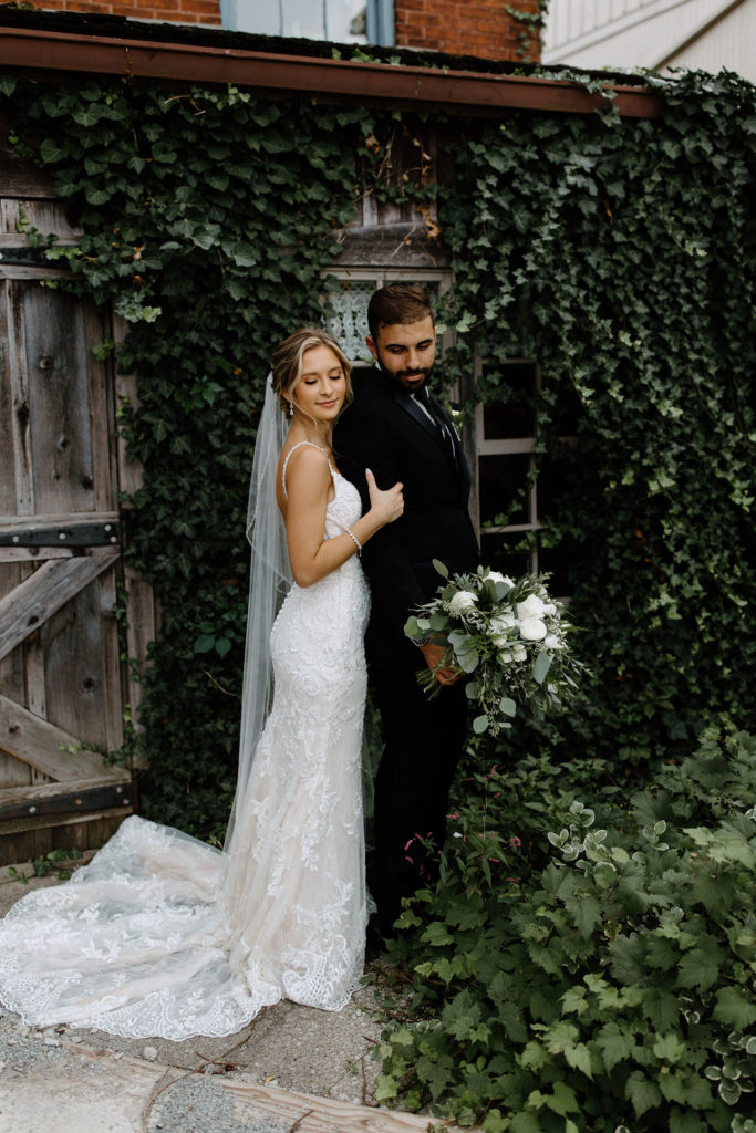 Bride and broom posing for wedding portraits before sage green and white color schemes wedding