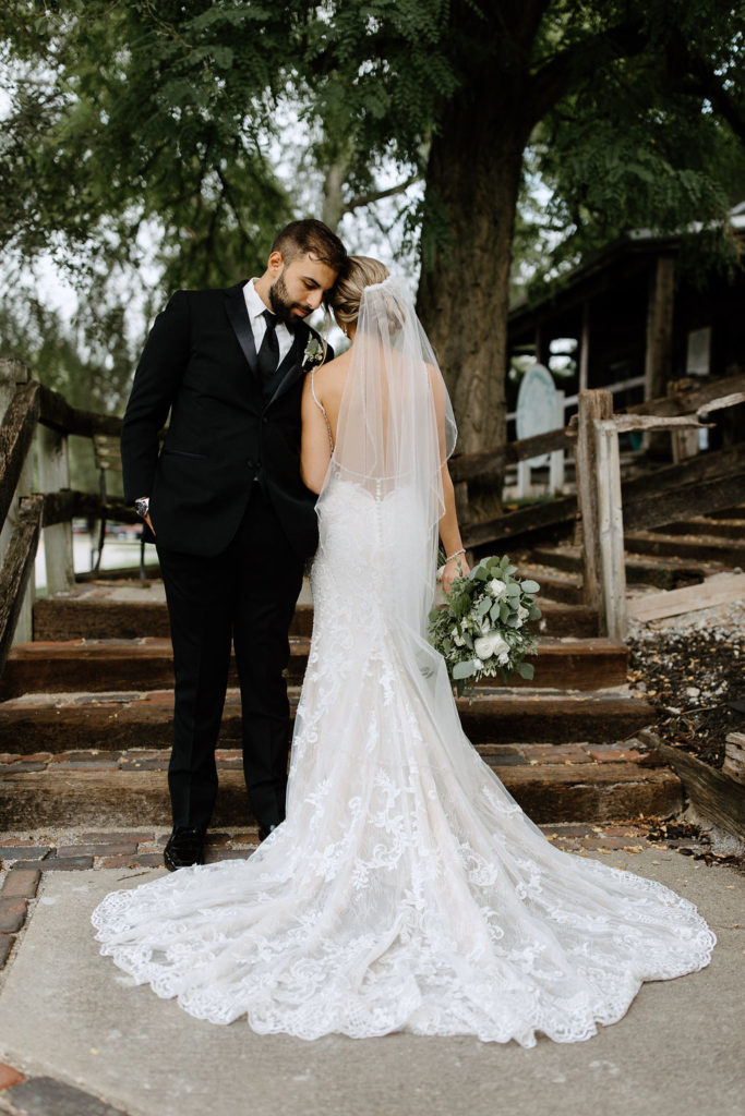 Bride and broom posing for wedding portraits before sage green and white color schemes wedding