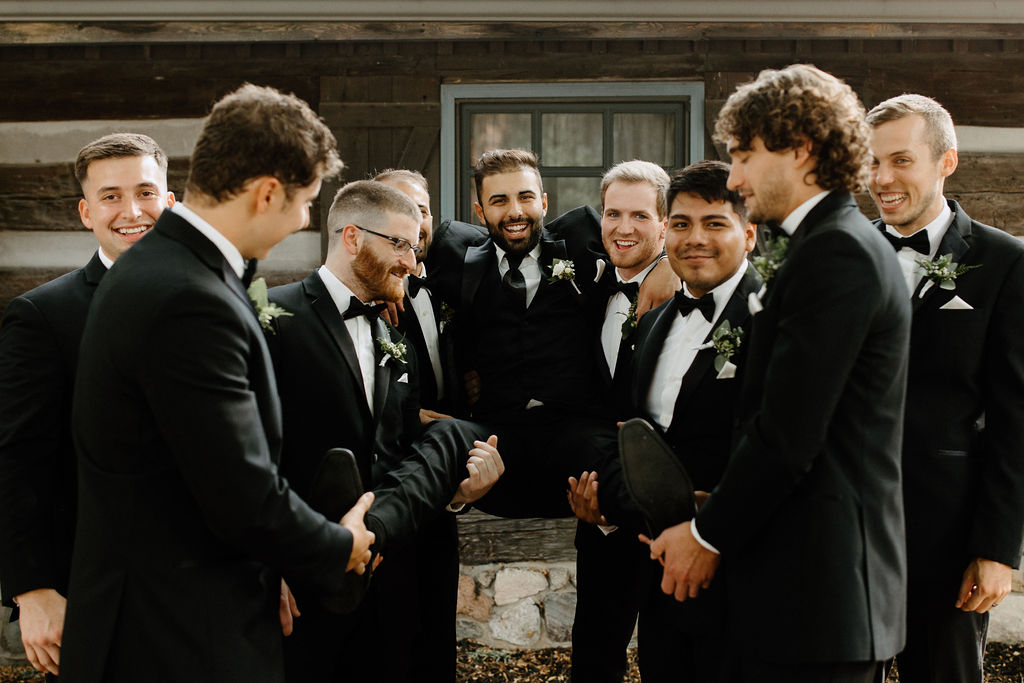 Groomsman portraits before Indiana wedding with groomsman lifting groom up