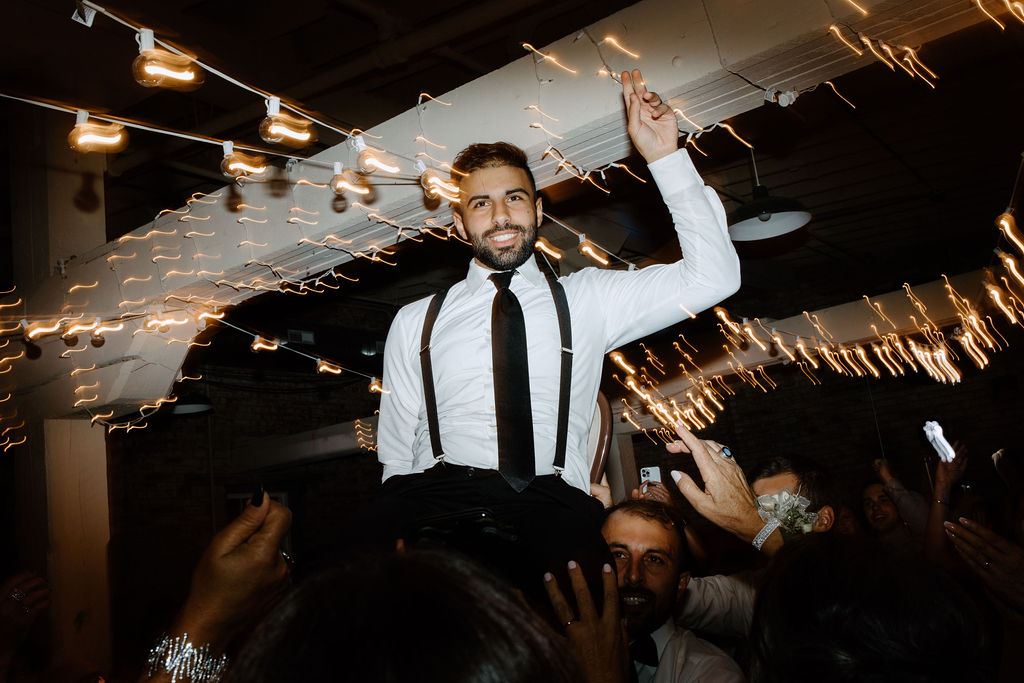 Groom being lifted in his chair during wedding reception