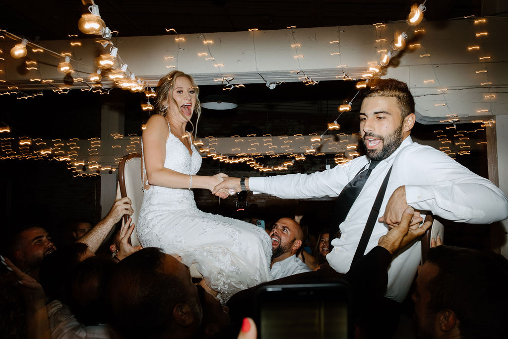 Bride and groom being lifted in their chairs during wedding reception