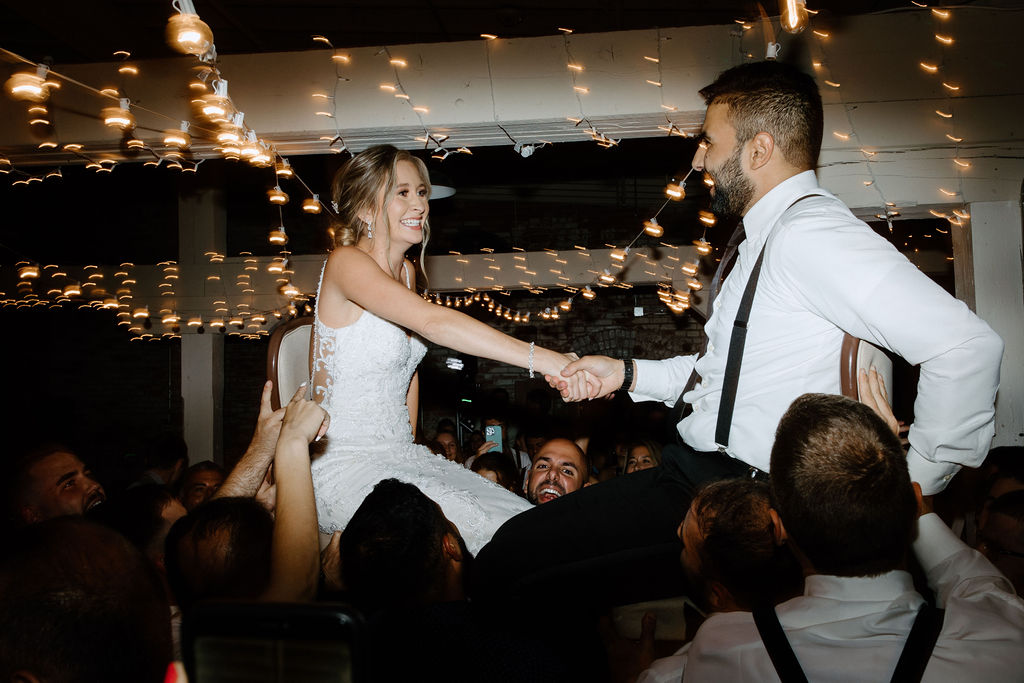 Bride and groom being lifted in their chairs during wedding reception