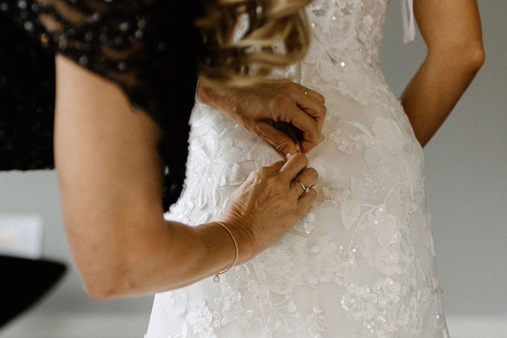 bride gettingdress zipped up before wedding