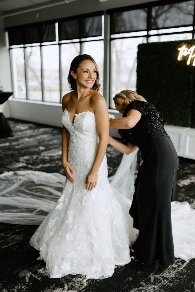 bride getting dress zipped up before wedding