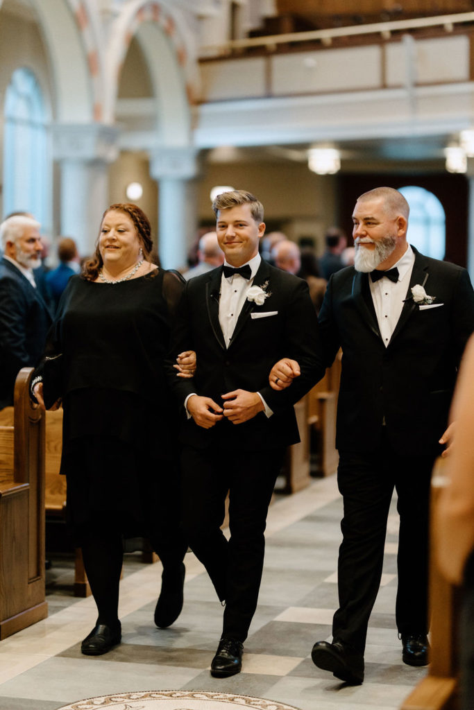 groom wlaking down the aisle witjh parents