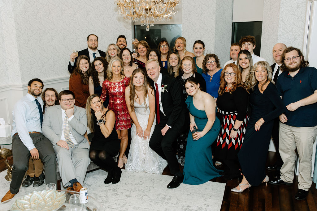 Bride and groom posing with family and friends after wedding