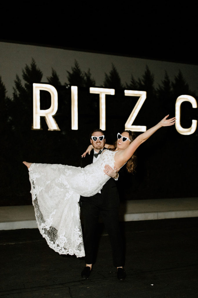 Bride and groom posing in front of Ritz Charles sign in Carmel, Indiana